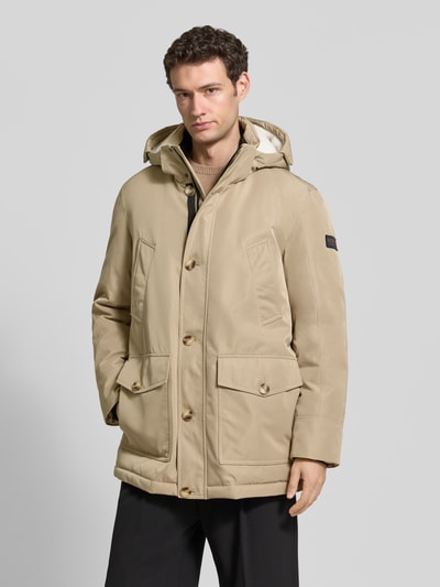 Männermodel trägt hellbeigen Parka mit Kapuze und Pattentaschen von MCNEAL, Regular Fit, Knopfleiste, verdeckter Reißverschluss, Nahaufnahme Oberkörper.