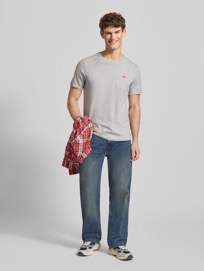 Männermodel trägt T-Shirt mit Label-Detail von Levi's®, graue Farbe, reine Baumwolle, Regular-Fit, gerippter Rundhalsausschnitt, Ganzkörperansicht von vorne. Rückenlänge bei Größe M: 69 cm.