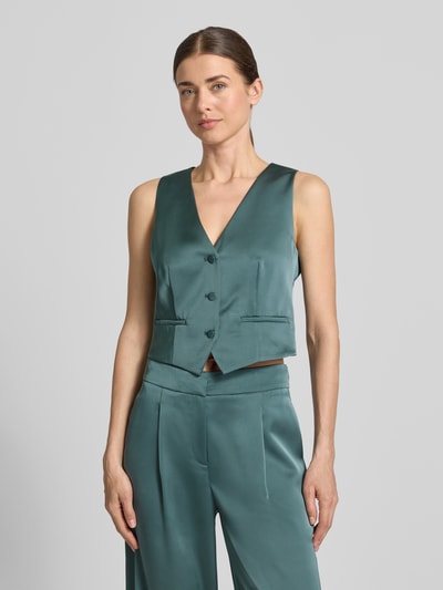 Frauenmodel trägt Weste aus Satin mit V-Ausschnitt von Jake*s Cocktail, Slim-Fit, Knopfleiste, Paspeltaschen, Rückenlänge 40 cm, Ganzkörperansicht von vorne.