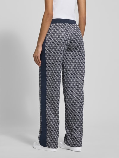 Frauenmodel trägt Wide Leg Sweatpants im Allover-Look Modell 'MAYA' von Guess Activewear mit elastischem Bund, Ganzkörperansicht Rückansicht.