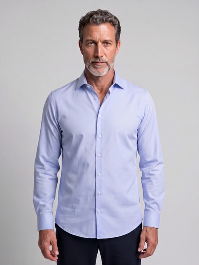 Männermodel trägt Slim Fit Business Hemd mit Kentkragen aus Feintwill von Seidensticker in Hellblau, glatte Textur, Ganzkörperansicht von vorne.