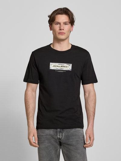 Männermodel trägt T-Shirt mit Logo und Rundhalsausschnitt von Jack & Jones in Schwarz, Regular Fit, reine Baumwolle, Ganzkörperansicht von vorne.