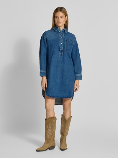 Vrouwenmodel draagt Oversized Jeanskleid uit lyocellmix van Armedangels, denimlook, oversized fit, midilengte, ronde hals, labelpatch, strikceintuur, korte knoopsluiting, lange mouw met manchet, recht zoom, borstzak. Ganzkörperansicht van voren.