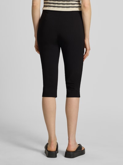 Modelka nosi Carprihose aus Viskose-Mix mit seitlichen Schlitzen von Jake*s Casual, czarny, krój slim fit, z rozcięciami po bokach, Szerokość w rozmiarze 36: 36 cm, długość nogawki od wewnątrz: 44 cm, widok całej sylwetki od tyłu.