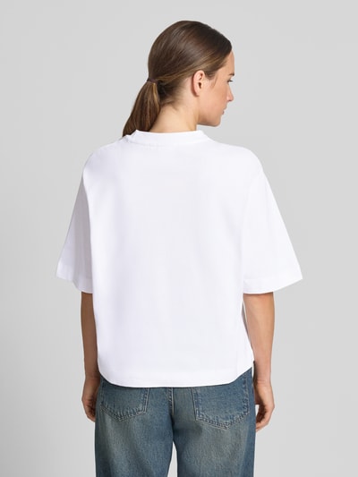 Frauenmodel trägt T-Shirt mit Motiv-Print und Ziersteinbesatz von Rich & Royal aus reiner Baumwolle, weiße Farbe, Ganzkörperansicht Rückansicht.