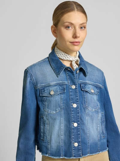 Vrouwenmodel draagt Cropped Jeansjacke mit Fransen van Marc Cain, mix van katoen en elastaan, blauwe tinten, knoopsluiting, borstzak, franjes, borstwijdte 50 cm, schouderbreedte 39 cm, ruglengte 49 cm, mouwlengte 60 cm, nahaufnahme bovenlichaam.