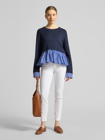 Frauenmodel trägt Strickpullover aus Viskose-Mix im 2-in-1-Look von Liu Jo White, Relaxed-Fit, Rundhalsausschnitt, Dunkelblau mit blauen Plisseedetails, Rückenlänge 55 cm, Ärmellänge 50 cm, Ganzkörperansicht von vorne.