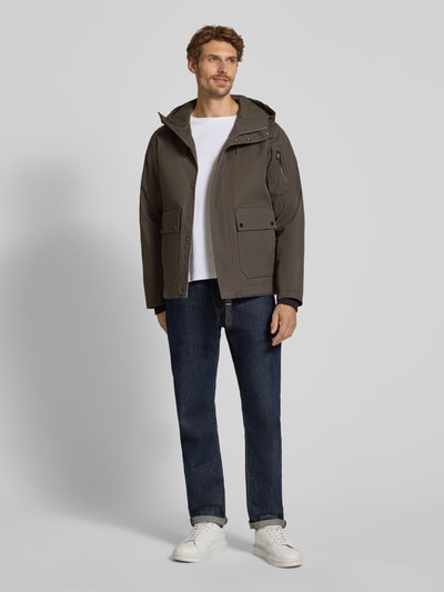 Męski model nosi kurtkę Regular Fit z mieszanki bawełny Model 'Globe Evo' od g-lab, kolor khaki, kaptur, kieszeń na rękawie, wpuszczane kieszenie, elastyczne zakończenia rękawów, długość tyłu w rozmiarze M: 90 cm, szerokość ramion w rozmiarze M: 44 cm, szerokość w rozmiarze M: 42 cm, długość rękawów w rozmiarze M: 66 cm, pełny widok z przodu.