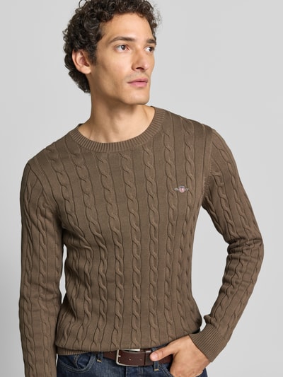Männermodel trägt Regular Fit Pullover aus reiner Baumwolle von GANT in Braun mit Strickstruktur, Nahaufnahme Oberkörper.