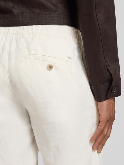 Männermodel trägt Slim Fit Leinenhose aus reinem linnen Modell 'Fabio' von Brax, effen, met label-applicatie en zakken, detailopname rugaanzicht.