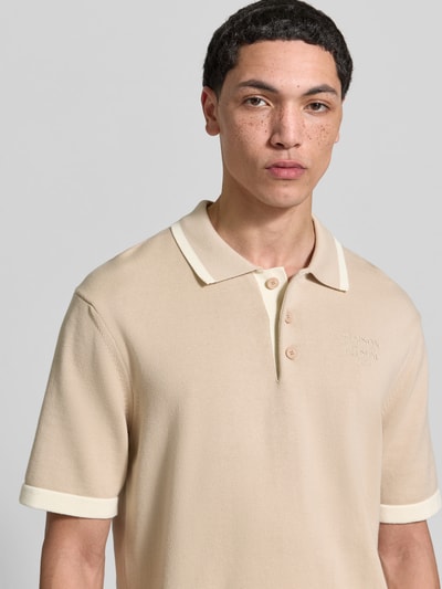 Männermodel trägt Regular Fit Poloshirt aus Baumwolle von MAISON KITSUNÉ in Beige, strukturierte Strick-Optik, Nahaufnahme Oberkörper.