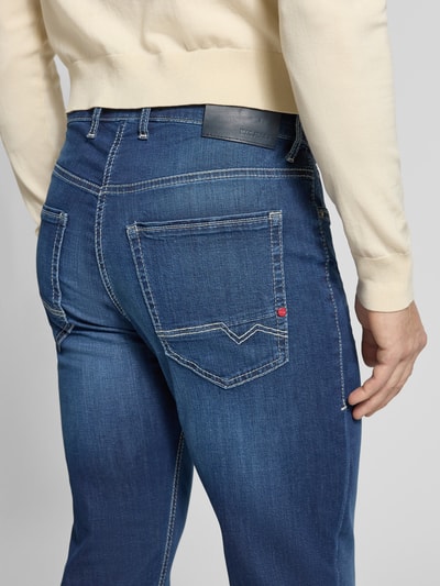 Mannelijk model draagt Straight Fit Jeans aus Baumwoll-Mix van MAC in donkerblauw met contraststiksels, 5-pocket-design en label-patch, katoen-elastaan-mix, knoop- en ritssluiting, detailopname achterkant.