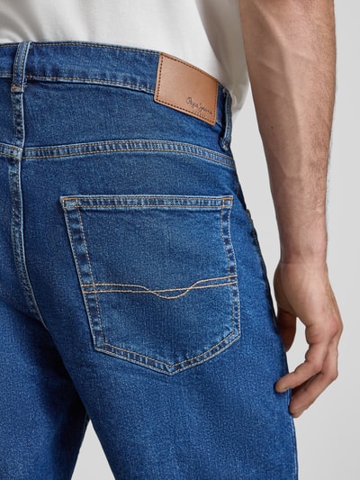 Männermodel trägt Regular Fit Jeansshorts aus Baumwoll-Mix Modell 'CASH BERMUDA' von Pepe Jeans, denim Optik, label patch, contrastnaden, metalen knoop, 5-pocket ontwerp, detailaufnahme rückansicht.