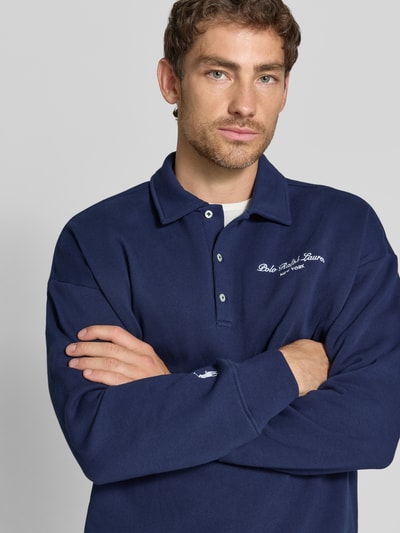 Männermodel trägt Relaxed Fit Sweatshirt aus mieszanka bawełny von Polo Ralph Lauren w kolorze granatowym, widoczna faktura materiału, nahaufnahme górnej części ciała.
