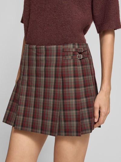 Frauenmodel trägt Minirock mit Falten Modell 'PUNK' von MANGO im karierten Allover-Look, Material-Mix mit Viskose, Nahaufnahme Oberkörper.