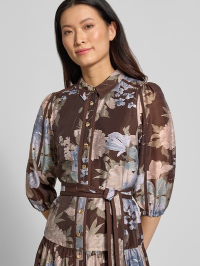 Vrouwenmodel draagt avondjurk uit mix van lyocell en linnen Model 'Gianna' van Forever New met bloemprint, getailleerde pasvorm, knoopsluiting, 3/4-mouw met elastische boorden, laagjeslook, maxilengte, ruglengte maat 36: 126 cm, borstwijdte 45 cm, mouwlengte 47 cm, detailopname bovenlichaam.