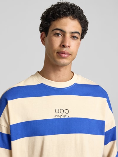 Männermodel trägt T-Shirt mit Streifenmuster Modell 'KAVEH' von Blend, relaxed Fit, blaue und beige Streifen, reine Baumwolle, Nahaufnahme Oberkörper.