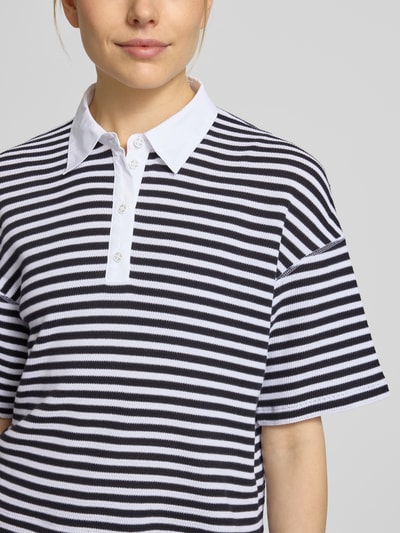 Frauenmodel trägt Relaxed Fit Oberteil in Strick-Optik mit Polokragen von Marc Cain, Reine Baumwolle, Schwarz-Weiß-Streifen, Kurzärmelig, Nahaufnahme Oberkörper