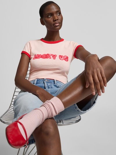 Frauenmodel trägt Cropped T-Shirt aus reiner Baumwolle von Kenzo in Rosa mit roten Akzenten, Slim Fit, Statement-Print, Rundhalsausschnitt, Rückenlänge bei Größe S 40 cm, Damen T-Shirt, Ganzkörperansicht von vorne.