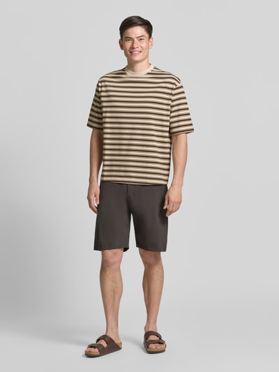Męski model nosi Relaxed Fit T-Shirt aus reiner Baumwolle Modell 'ASPEN 2' von SELECTED HOMME w beżowo-brązowe paski, gładka faktura, Ganzkörperansicht von vorne.
