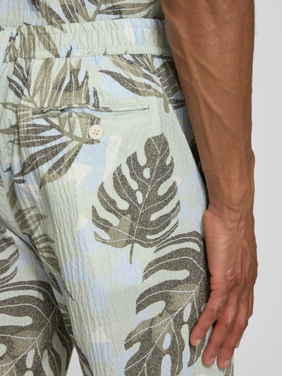 Männermodel trägt Shorts im Allover-Look von Lindbergh mit tropischem Blätter-Muster, Baumwoll-Elasthan-Mix, Nahaufnahme Hüfte.