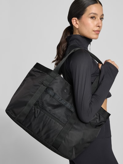 Vrouwenmodel draagt shopper met logodetail van Under Armour, zwarte stof, rechthoekige vorm, dames, vooraanzicht heuphoogte