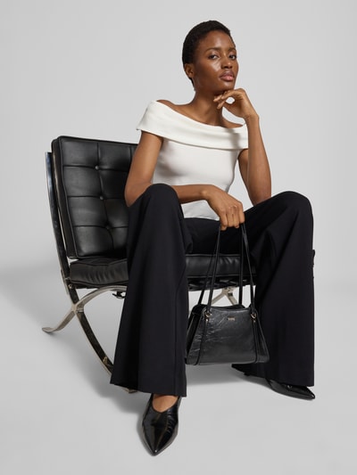 Frauenmodel trägt Shoulder Bag in Leder-Optik Modell 'Xena' von GUESS mit Logo-Detail, schmalen Schulterriemen, Schwarz, Nahaufnahme Oberkörper.