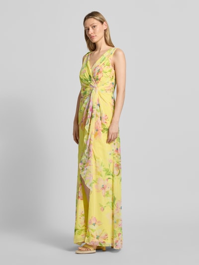 Frauenmodel trägt Maxikleid in Wickel-Optik mit V-Ausschnitt von Adrianna Papell, gelber Allover-Look, fließender Stoff, Ganzkörperansicht von vorne. Rückenlänge bei Größe 36: 148 cm, Brustweite bei Größe 36: 41 cm, taillierter Schnitt.