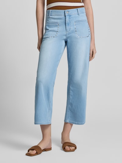 Frauenmodel trägt Wide Fit Jeans in verkürzter Passform Modell 'Linn' von Angels, hellblauer elastischer Baumwoll-Mix mit Nietenbesatz und aufgesetzten Taschen, Ganzkörperansicht von vorne.