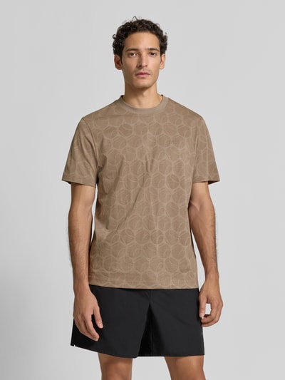 Męski model nosi Regular Fit T-Shirt aus reiner Baumwolle od BOSS Green w jasnobrązowym kolorze z geometrycznym wzorem, gładka tekstura, całkowity widok z przodu.