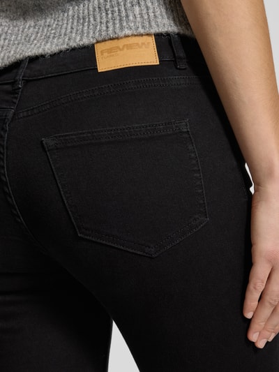 Frauenmodel trägt Flared Jeans mit mittelhohem Bund von Review in schwarzer Waschung, Baumwoll-Mix mit Stretch, Detailaufnahme Rückansicht.