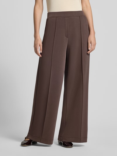 Kobiece modelka nosi spodnie 'Wide Fit Hose mit Viskose-Anteil' od COMMA, brąz, obszerne nogawki, elastyczna mieszanka materiałów z dodatkiem wiskozy, ozdobna kokarda na pasie, szerokość w rozmiarze 36: 37 cm, długość wewnętrzna nogawki w rozmiarze 36: 77 cm, widok na całe ciało z przodu.