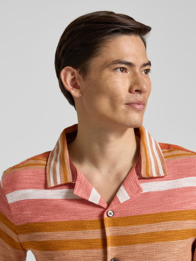 Männermodel trägt Slim Fit Freizeithemd mit Reverskragen Modell 'Carlo' von Zuitable, Allover-Streifenmuster in Orange und Rosa, Nahaufnahme Oberkörper. Baumwoll-Mix mit Viskose-Anteil, Größe M.