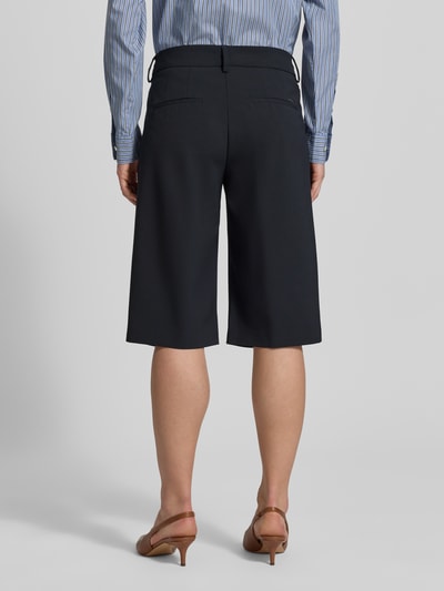 Männermodel trägt Loose Fit Bermudas mit Knopfverschluss Modell 'MILLA' von BRAX, mieszanka materiałów z dodatkiem żywej wełny, długość wewnętrzna nogawki 36 cm, szerokość w rozmiarze 36: 41 cm, kieszenie boczne i z tyłu, widok całej sylwetki z tyłu.