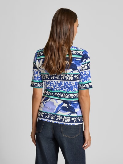 Frauenmodel trägt Damen T-Shirt mit Allover-Muster, Baumwoll-Mix mit Stretch-Anteil, Regular-Fit, Rundhalsausschnitt von Betty Barclay, Rückenlänge 44 cm bei Größe 36, Farbgebung in Blau- und Weißtönen, Ganzkörperansicht Rückansicht.