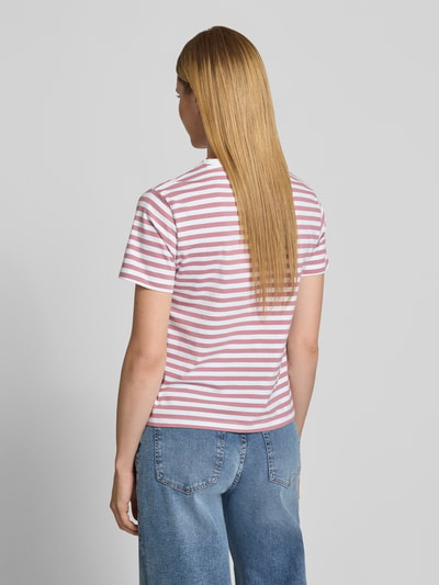 Modelka nosi damski t-shirt z mieszanki bawełny i elastanu, krój regular fit, okrągły dekolt, model 'NORA' od VILA, długość tyłu 57 cm, różowo-białe paski, zdjęcie całej sylwetki z tyłu.