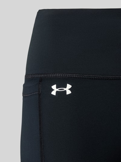 Frauenmodel trägt Flared Fit Leggins mit breitem Bund Modell 'Motion' von Under Armour, Elastischer-Material-Mix, Beintasche, Logo-Print, Nahaufnahme Oberkörper.