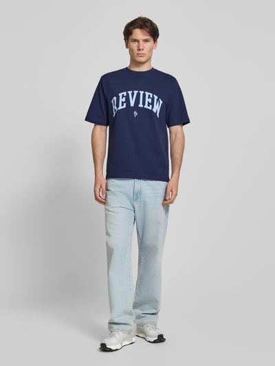 Männermodel trägt T-shirt mit labelprint und ronde hals van REVIEW aus puur katoen, regular fit, ruglengte bij maat M 69 cm, ganzlichaamsvooraanzicht