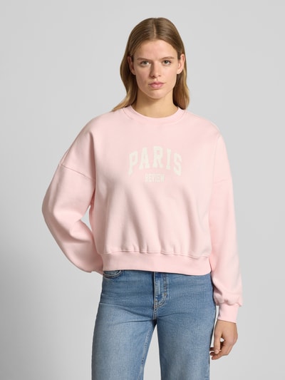 Frauenmodel trägt Sweatshirt mit Label-Print und Rundhalsausschnitt von Review, Baumwoll-Mix im Relaxed-Fit, zartrosa Farbe, Ganzkörperansicht von vorne.