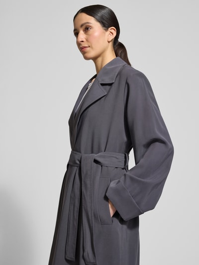 Frauenmodel trägt Trenchcoat aus Viskose-Mix mit Bindegürtel von Jake*s Casual, Relaxed-Fit, Reverskragen, Nahaufnahme Oberkörper. Rückenlänge 113 cm, Schulterbreite 42 cm, Brustweite 48 cm, Ärmellänge 61 cm.