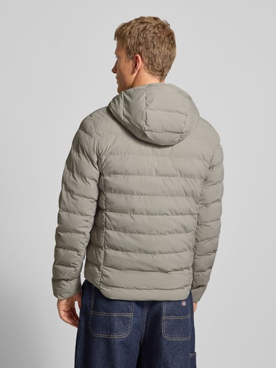 Männermodel trägt Steppjacke mit Brusttasche und Label-Detail Modell 'Foundation' von G-Star in Grau, Rückenansicht, Regular-Fit, Kapuze, glatte Oberfläche, Größenangaben: Rückenlänge 70 cm, Schulterbreite 46 cm, Brustweite 56 cm, Ärmellänge 70 cm. Ganzkörperansicht Rückansicht.