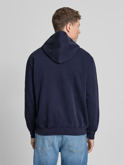 Männermodel draagt Hoodie met Logo en Kangoeroezak van GAP in donkerblauw, katoenmix, regular fit, rugaanzicht, ruglengte maat M 69 cm, mouwlengte 64 cm. Ganzkörperansicht Rückansicht.