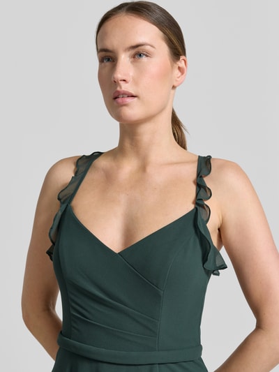 Frauenmodel trägt dunkelgrünes Cocktailkleid aus Chiffon mit Volants von V.M., V-Ausschnitt, Drapierungen, Nahaufnahme Oberkörper, Damen, A-Linie, Midikleid, Rückenlänge 109 cm, Brustweite 34 cm.