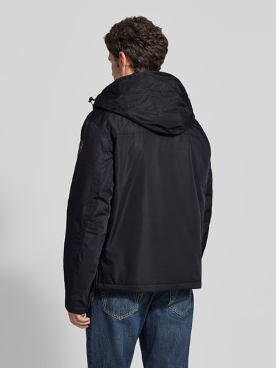 Männermodel trägt Jacke mit Kapuze und kurzem ritssluiting van Napapijri in zwart, recht model, labelpatch en klepzak, Ganzkörperansicht Rückansicht. Ruglengte maat M 73 cm, schouderbreedte 53 cm, borstwijdte 60 cm, mouwlengte 64 cm.