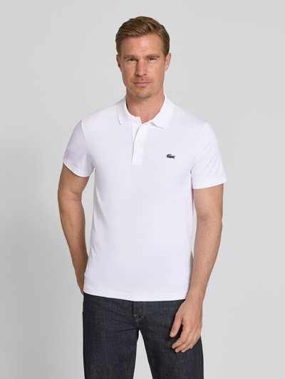 Männermodel trägt Regular Fit Poloshirt aus Baumwoll-Mix von Lacoste, Optik: Unifarben, Logo-Patch, Polokragen, Kurzarm, Ganzkörperansicht von vorne.