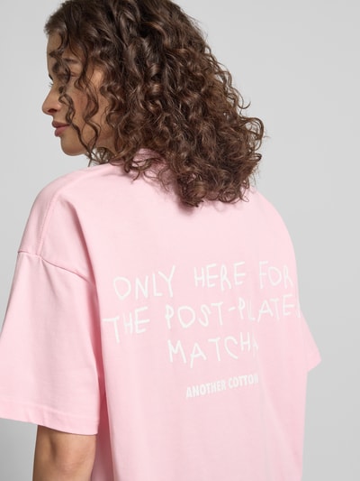 Frauenmodel trägt Damen T-Shirt mit Logo-Stitching von ANOTHER COTTON LAB aus reiner Baumwolle in Rosa, lockerer Schnitt, Rückenlänge 66 cm, Ganzkörperansicht Rückansicht.