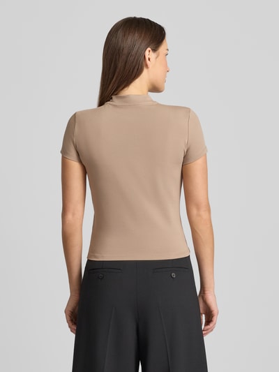 Vrouwenmodel draagt Slim Fit T-Shirt met Allover-Strasssteinbesatz van Guess in beige met korte mouwen en opstaande kraag, rugaanzicht.