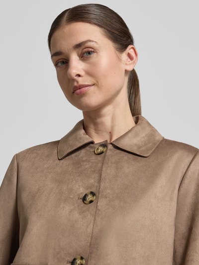 Modelka kobieca nosi Regular Fit Jacke in Lederoptik mit Umlegekragen od s.Oliver BLACK LABEL w kolorze jednolitym, z długimi rękawami, zapięciem na pojedynczy rząd guzików i kieszeniami, wykonane z welurowego materiału imitującego skórę; zbliżenie na górną część ciała.
