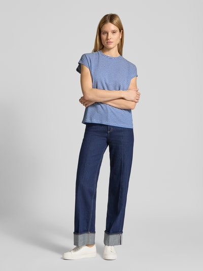 Vrouwenmodel draagt Loose Fit T-shirt uit zuiver biologisch katoen van Armedangels, blauw gestreept all-over motief, korte vleermuismouwen, ronde hals, dames T-shirt met loose fit pasvorm, structuur: glad katoen, voorkant compleet zichtbaar, fullbodyvoorzijde.