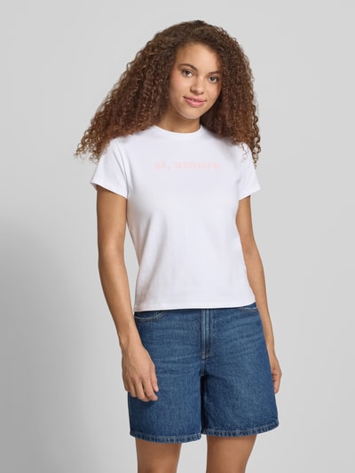 Frauenmodel trägt T-Shirt mit Print und Rundhalsausschnitt von REVIEW aus Baumwoll-Elasthan-Mix, Regular-Fit, weiße Farbe, Rückenlänge 51 cm bei Größe S, Ganzkörperansicht von vorne.